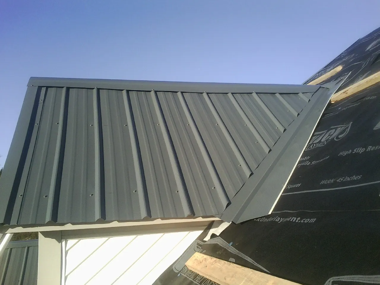Gray metal roof panels going on over a garage gable in Westerly