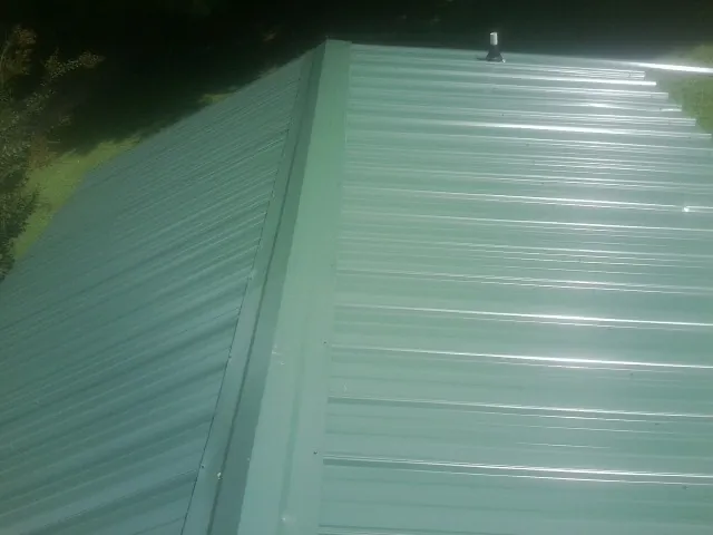 New green metal panels meeting at the ridge of a roof — Flat Roof Repair work by our crew in Westerly