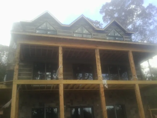 Dormers and porch framing on a large log home under construction — Roof Coating work by our crew in Westerly