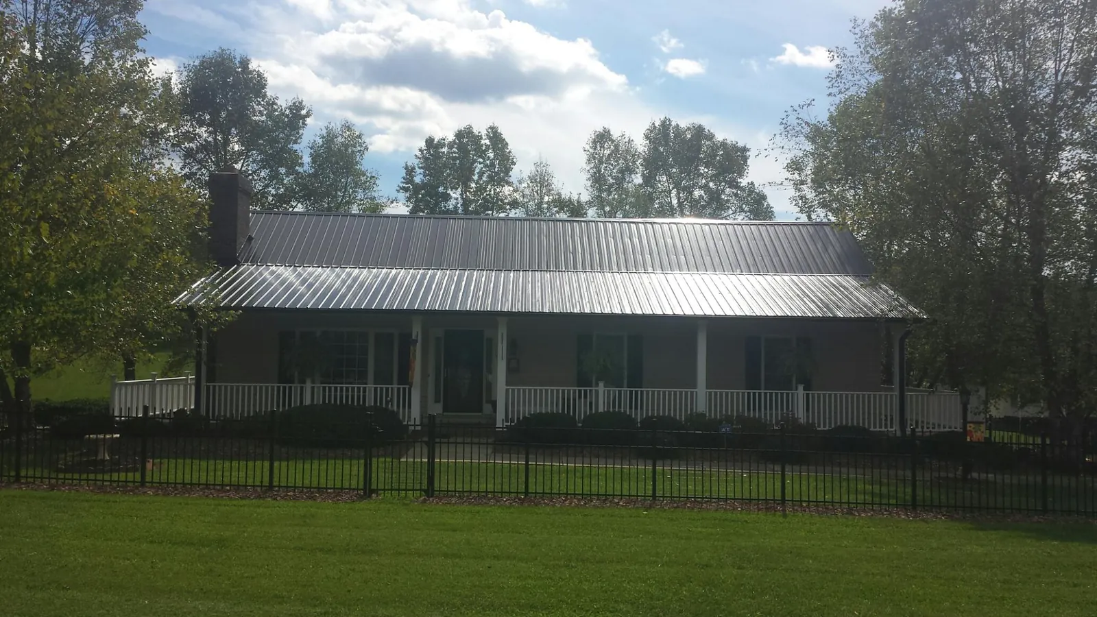 Gray metal roof on a brick ranch with a full width front porch — Gutter Guard Installation work by our crew in Westerly