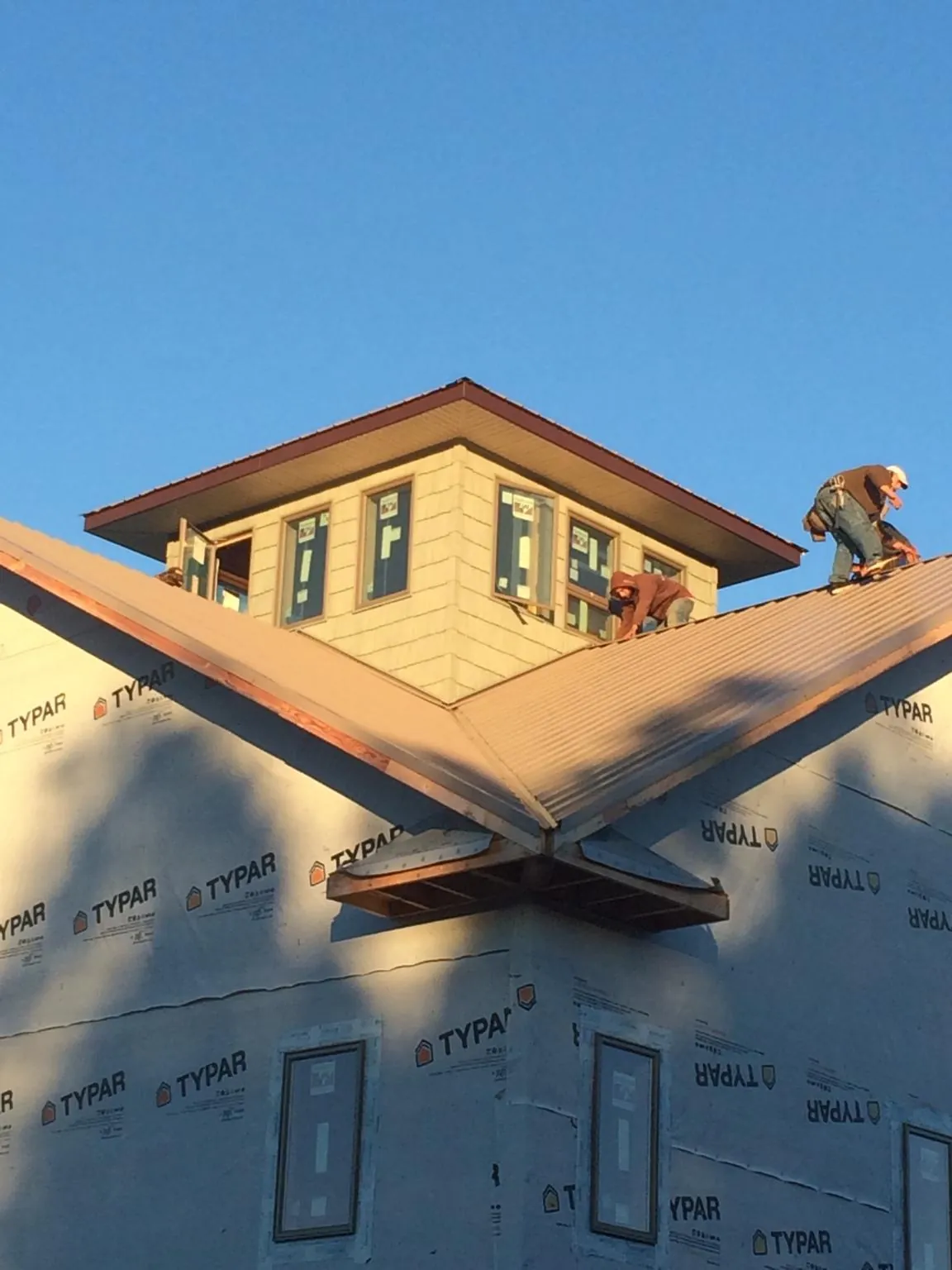 Roofers working around a rooftop cupola on a new metal roof at sunset — Roof Waterproofing in Westerly by Roofing Brothers